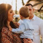 a man and woman holding a baby in a park