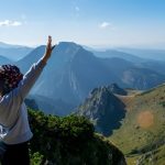 a person standing on top of a mountain with their arms in the air